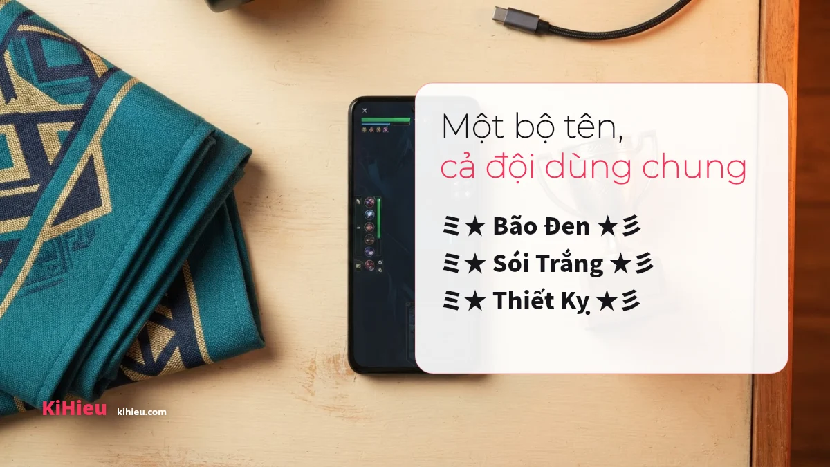 Khăn hoạ tiết xanh và điện thoại trên bàn gỗ, kèm thẻ trắng in ba tên clan mẫu cùng một khung kí tự